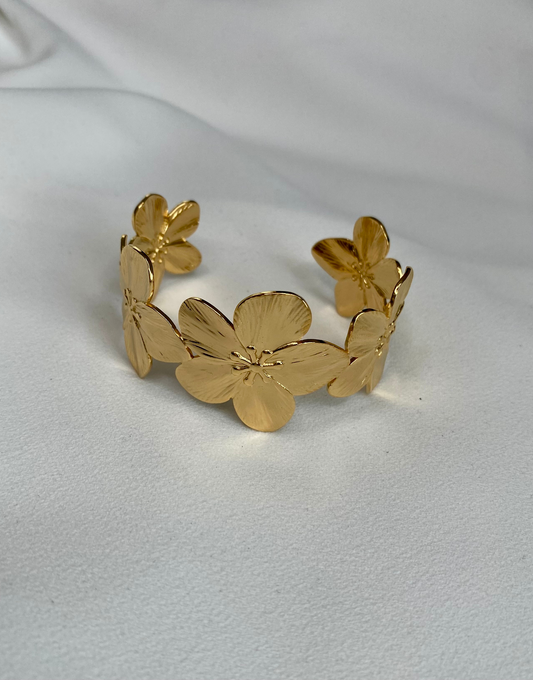 Close-up view of the ABYDOS Flower Cuff Bracelet, featuring an elegant design of detailed floral patterns in 18k gold plating over stainless steel, showcased on a soft white fabric background.