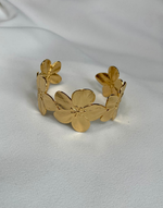 Cargar imagen en el visor de la galería, Close-up view of the ABYDOS Flower Cuff Bracelet, featuring an elegant design of detailed floral patterns in 18k gold plating over stainless steel, showcased on a soft white fabric background.
